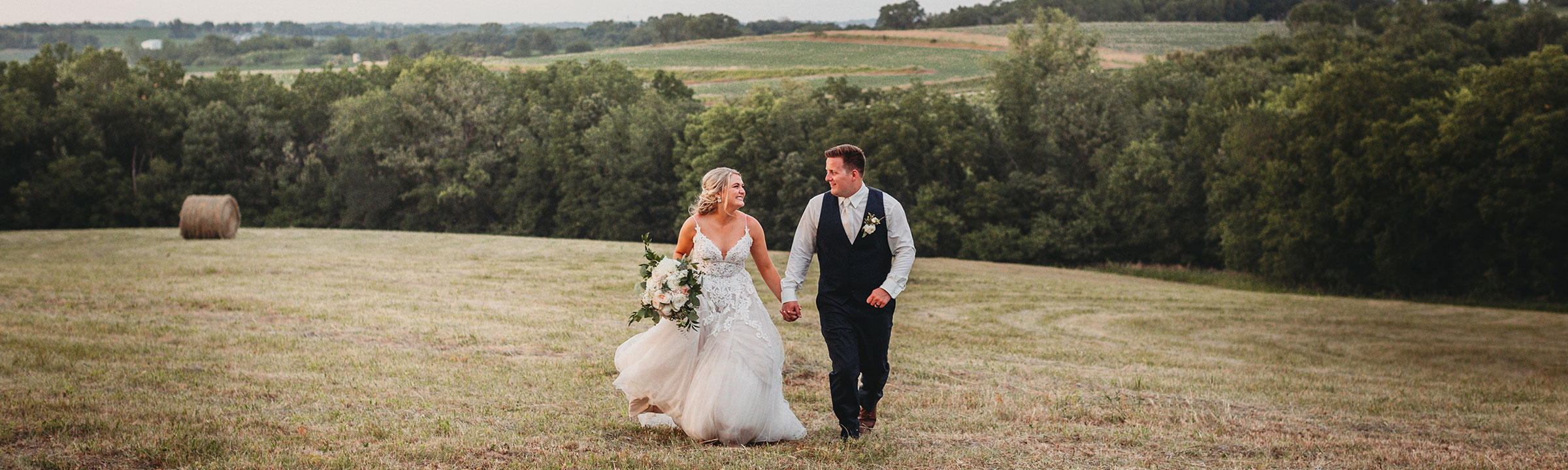 Bride and groom running in the field holding hands